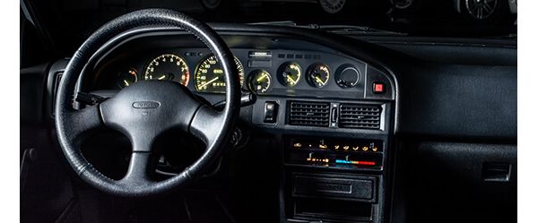 Cockpit des Corolla GTi von 1992 mit Drei-Speichen-Lenkrad, schwarzem Armaturenbrett und gelb-grün leuchtenden Instrumenten