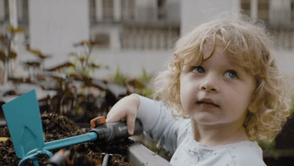 Ein junges Kind hält ein Gartenwerkzeug in der Hand und arbeitet in einem Beet