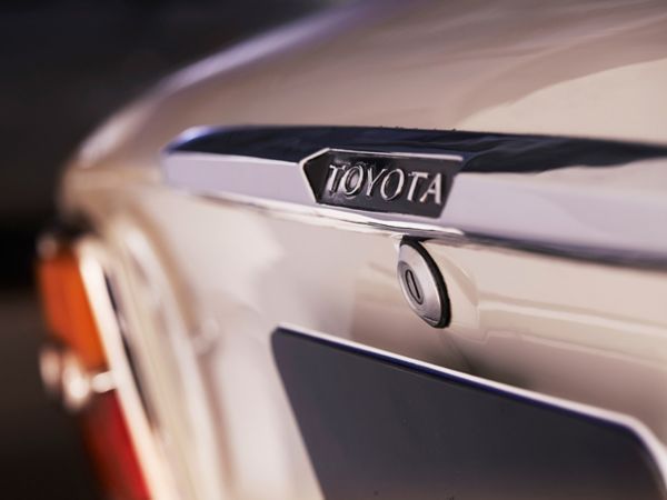 Detailaufnahme eines Toyota-Logos auf dem Kofferraumdeckels eines silbernen Oldtimers