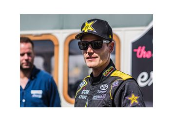 Portrait von Fredric Aasbo in schwarzem Overall mit Toyota Logo, schwarzer Kappe und Sonnenbrille.
