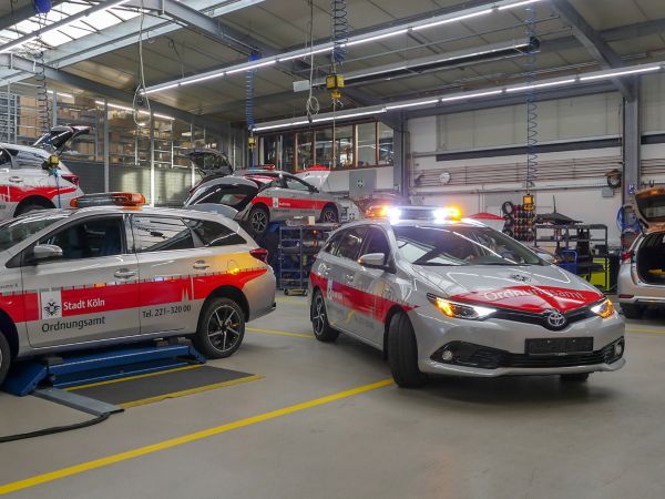 zahlreiche Corollas stehen in einer Halle und sind mit Polizei-Folierung foliert