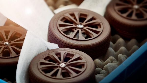 Kleine Lexus Reifen aus Schokolade gefertigt liegen in einer Schachtel auf Kakaobohnen