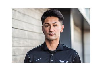 Portrait von Ken Gushi in schwarzem Polohemd mit Toyoto und Nike Logo auf der Brust.
