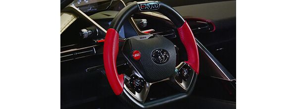 Schwarzes Sportlenkrad des Toyota FT1 mit roten Griffstücken rechts und links sowie weiteren roten Akzenten