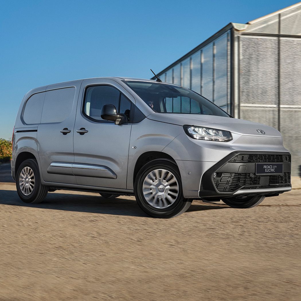 PROACE CITY Electric jedzie obok hali przemysłowej.