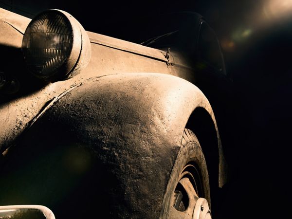 Nahaufnahme des Kotflügels und Vorderlichts eines extrem verwitterten und staubigen Toyoda AA von 1936, schwarzer Hintergrund