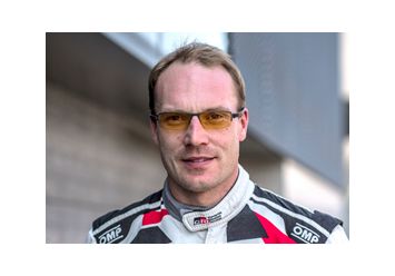 Portrait von Jari Matti Latvala in weiß schwarzem Rennanzug mit roten Akzenten und gelb getönter Brille.