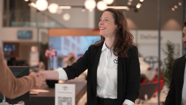 Female Toyota employee shaking hand with customer