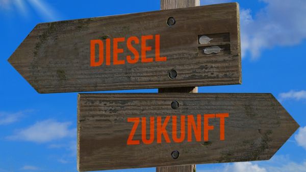 Zwei hölzerne Schilder an einem Wegweiser mit entgegengesetzten Pfeilen und den Aufschriften Diesel und Zukunft