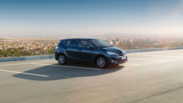 Ein schwarzer Toyota Verso, der an einem klaren Tag auf einem leeren Dach mit Blick auf die Skyline der Stadt geparkt ist.