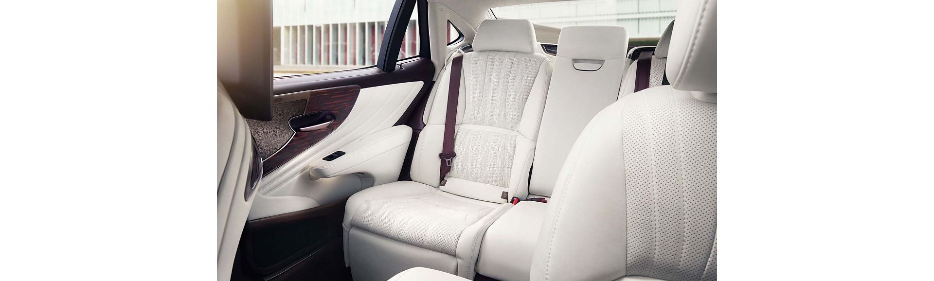 Geräumiger und luxuriöser Rücksitz eines Lexus LS, mit weißem Lederbezug mit perforierten Details und einem Sicherheitsgurt
