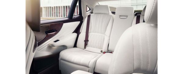 Geräumiger und luxuriöser Rücksitz eines Lexus LS, mit weißem Lederbezug mit perforierten Details und einem Sicherheitsgurt