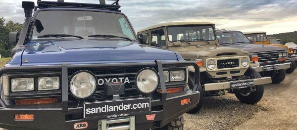 Mehrere ältere Generationen des Land Cruisers stehen nebeinander. Teilweise sind Kuhfänger und weiteres Zubehör angebracht. 