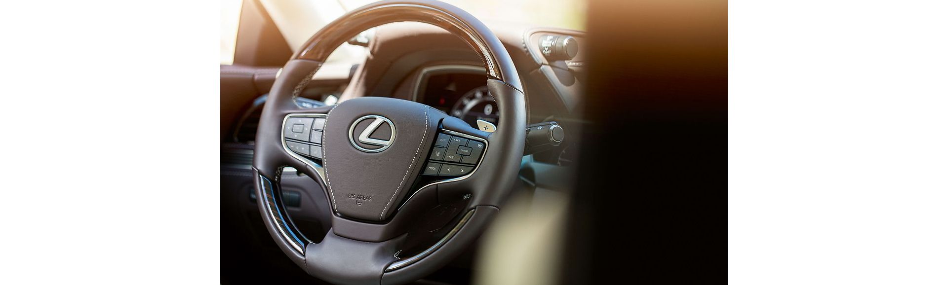 Nahaufnahme eines Lexus-Lenkrads mit Bedienelementen für Audio- und Tempomatfunktionen und eleganter Lederausstattung.