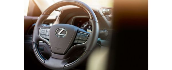 Nahaufnahme eines Lexus-Lenkrads mit Bedienelementen für Audio- und Tempomatfunktionen und eleganter Lederausstattung.