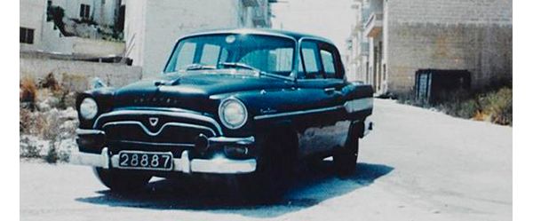 Farbfoto aus den 60er-Jahren: ein schwarzer Toyopet auf einer Straße vor einem südländischen Wohnhaus
