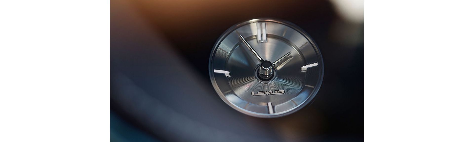 Nahaufnahme der Armaturenbrettuhr eines Lexus LS mit elegantem Silberdesign und dem Lexus-Logo, das die moderne Ästhetik unterstreicht.