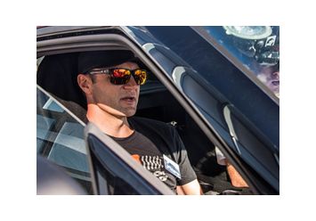 Blick durch das Beifahrerfenster auf Townsend Bell in schwarzem T-Shirt und orangener Sonnenbrille.