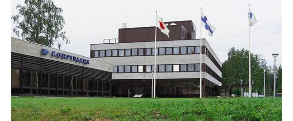 Modernes zweistöckiges Bürogebäude mit dem Schriftzug „Korpivaara“, davor wehen unter anderem die japanische und finnische Nationalflagge im Wind
