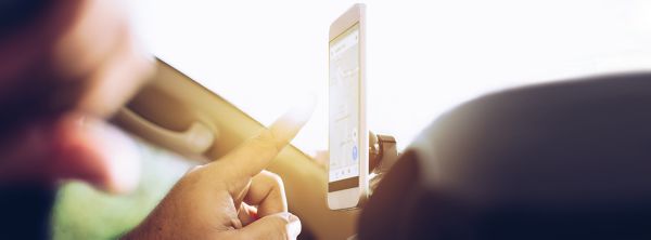Eine PerEin Smartphone mit geöffneter Navigationsanwendung ist im Fahrzeug installiert und zeigt die Funktion moderner Auto-Apps.