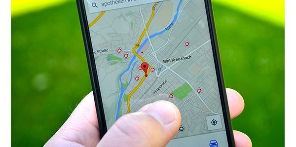 Ein Nutzer betrachtet auf dem Handy eine Stadtkarte mit Positionssymbolen, wie sie in vielen Auto-Apps zur Orientierung genutzt wird.