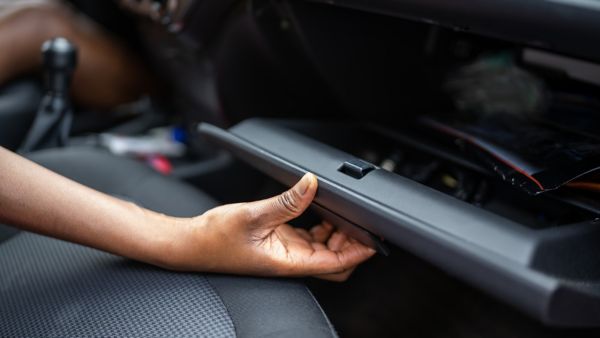 Eine Person öffnet das Handschuhfach eines Autos, in dem häufig die Zulassungsbescheinigung Teil I aufbewahrt wird.