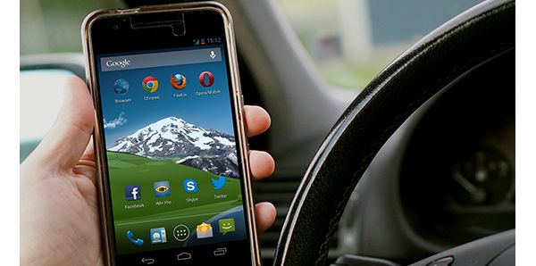 Eine Person hält ein Smartphone mit geöffneter App-Übersicht im Auto und nutzt verschiedene Anwendungen auch unterwegs.