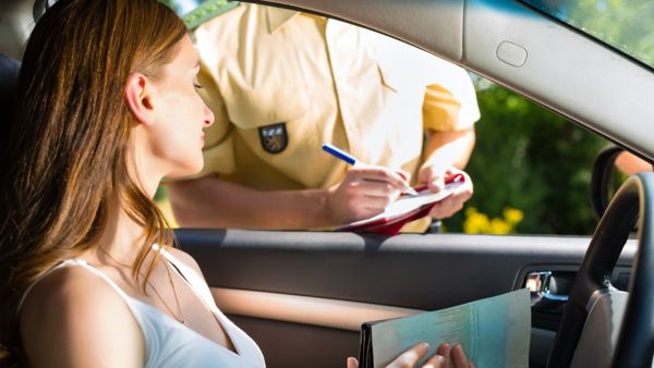 Eine Autofahrerin wird bei einer Verkehrskontrolle von der Polizei überprüft und hält ihre Zulassungsbescheinigung bereit.