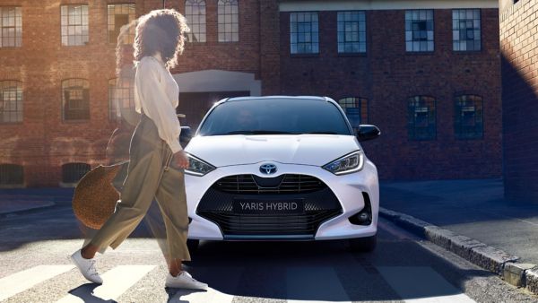 Woman crossing road in front of Toyota Yaris