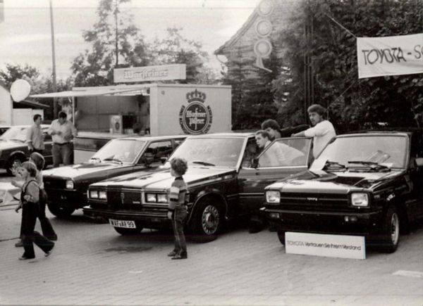 Ein Schwarzweiß-Bild von einem Innenhof mit mehreren alten Toyota-Fahrzeugen