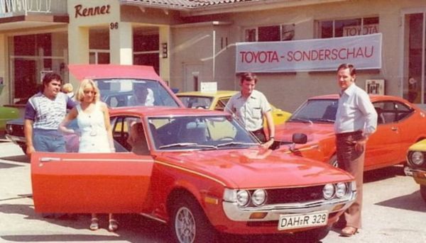Vier Personen stehen neben einem roten Toyota aus dem Jahr 1979 mit offenen Türen