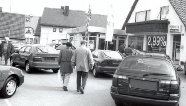 Schwarzweiß-Bild von einem Innenhof mit Toyota-Fahrzeugen und zwei Personen in der Mitte