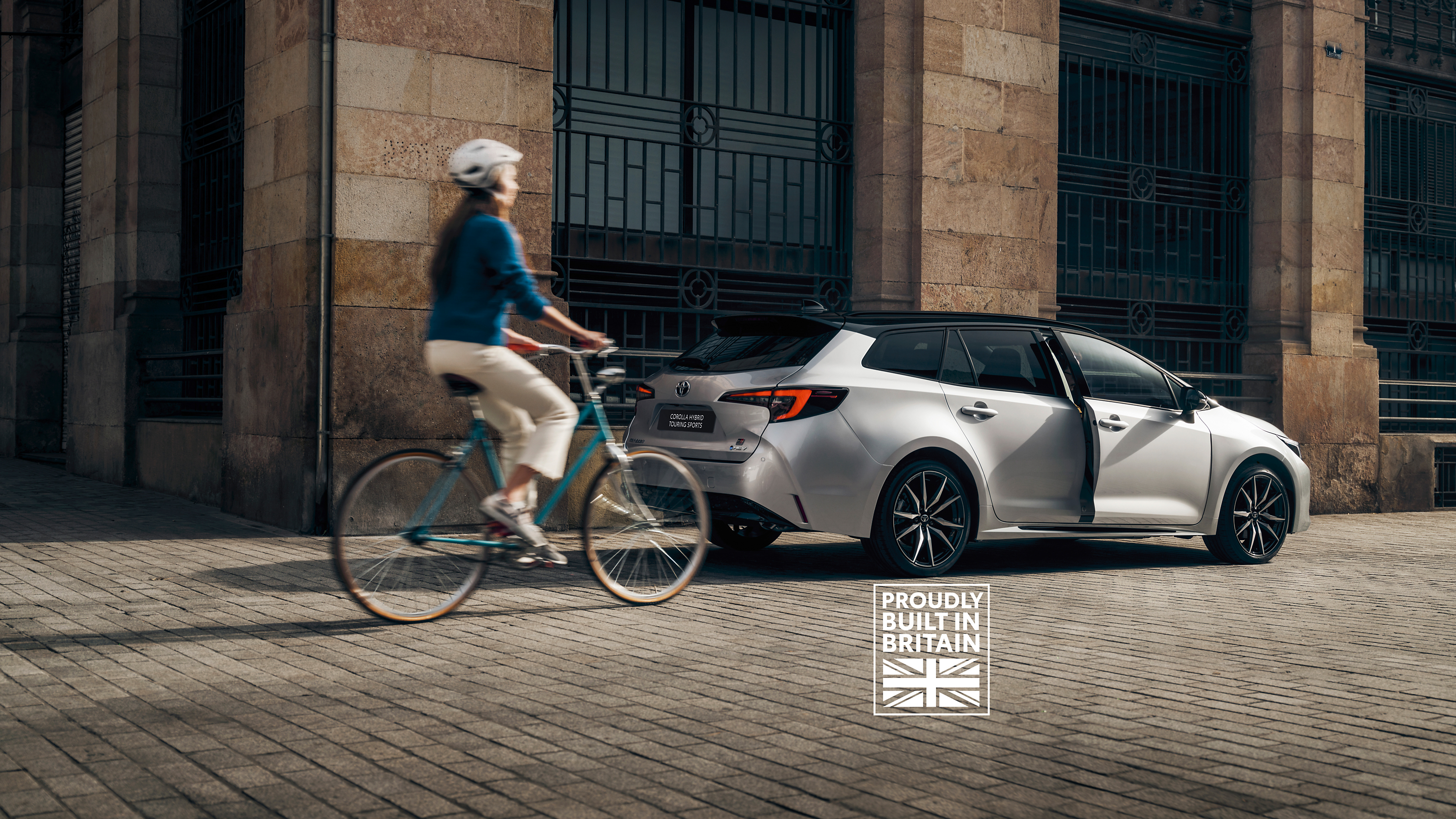 A cyclist rides past a Toyota Corolla Touring Sports