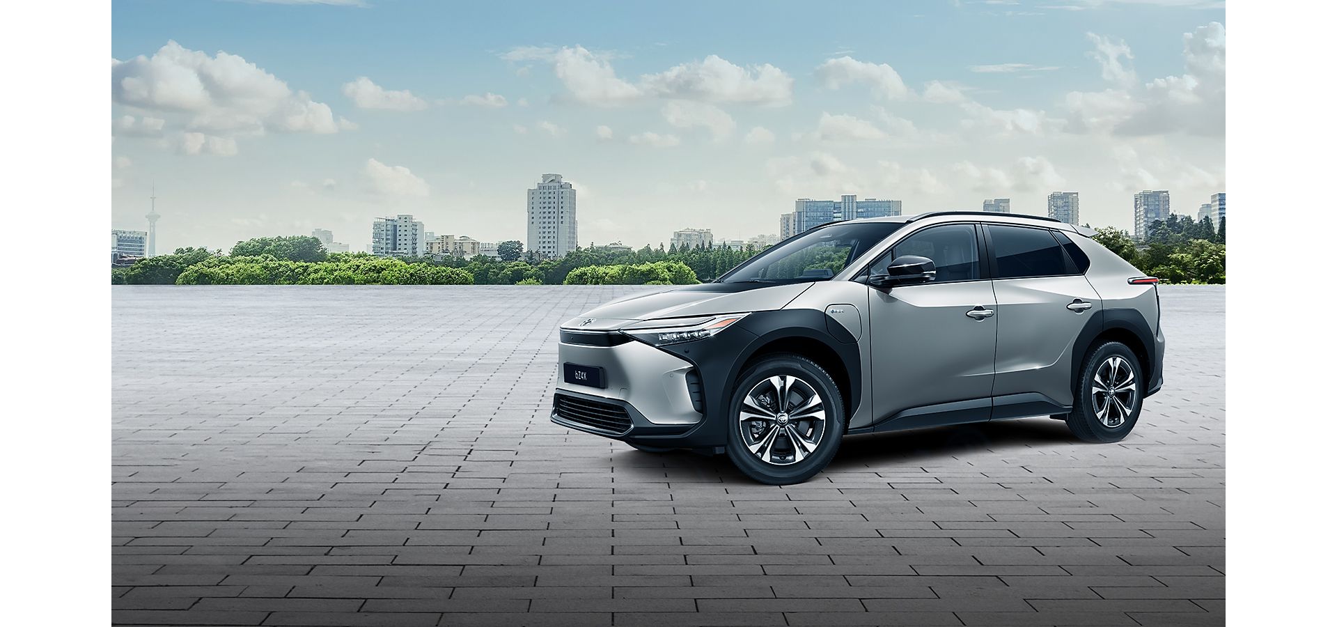 Zilveren Toyota bZ4X elektrische SUV met een skyline van de stad op de achtergrond.