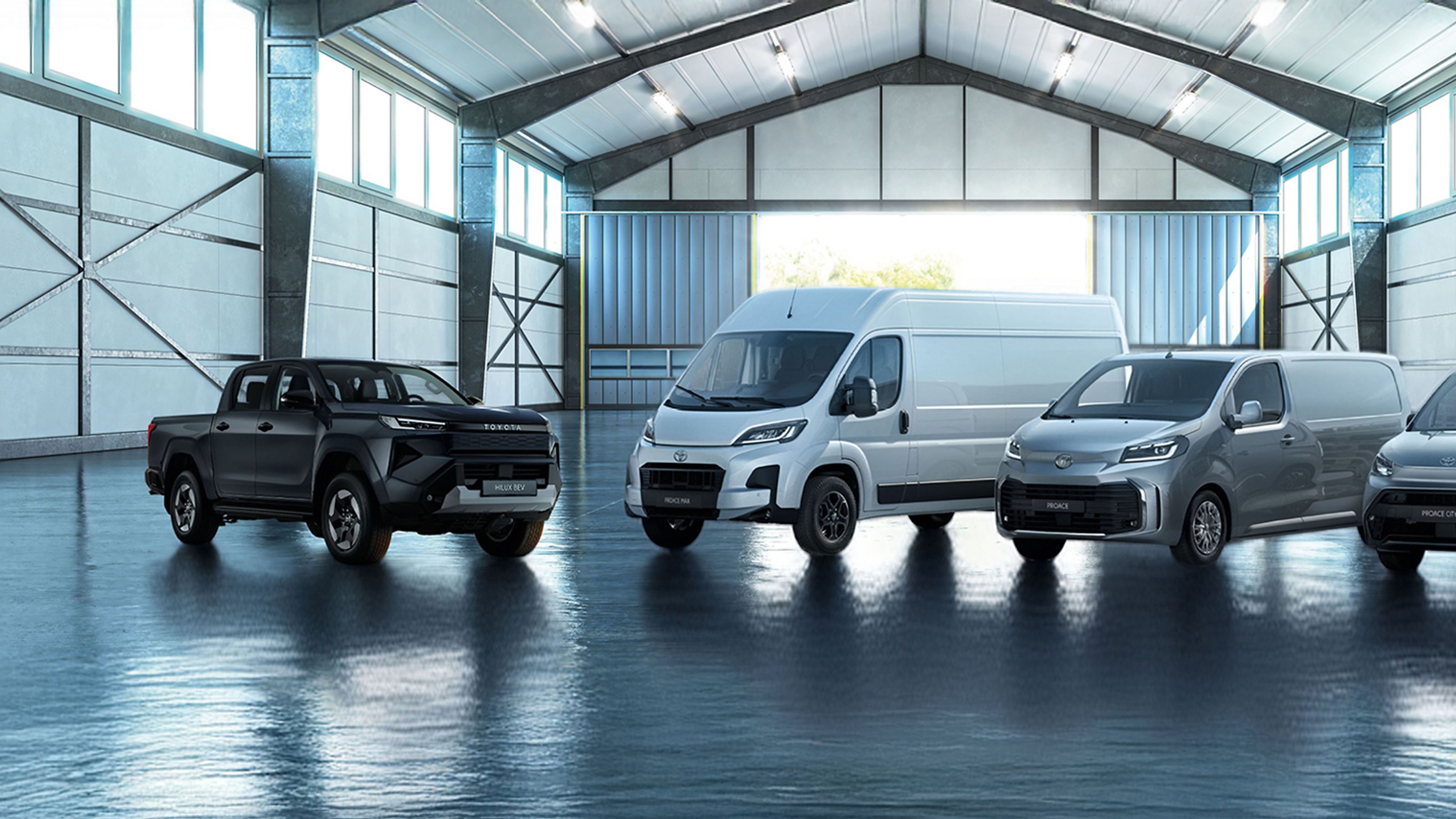 Drie Toyota Proace's geparkeerd voor gestapelde houten pallets.