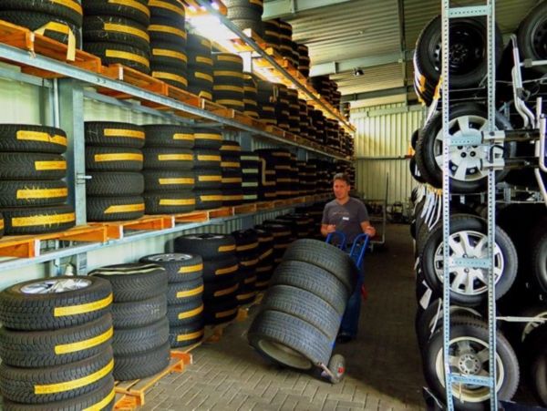 Eine Reifenhalle mit Toyota-Rädern. Im Mittelpunkt ist ein Mitarbeiter, der 4 Räder transportiert