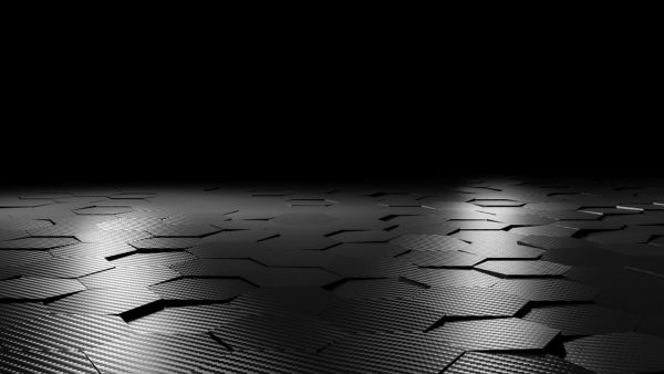Schwarze Platten in Form eines Hexagons angeordnet auf einem Boden mit schwarzen Hintergrund und schwacher Beleuchtung.