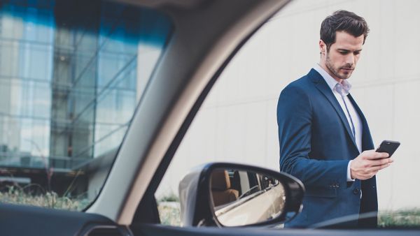 A man walking towards a parked Lexus