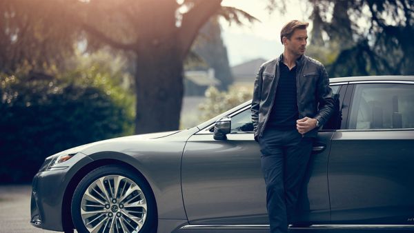 man leaning on a parked Lexus car