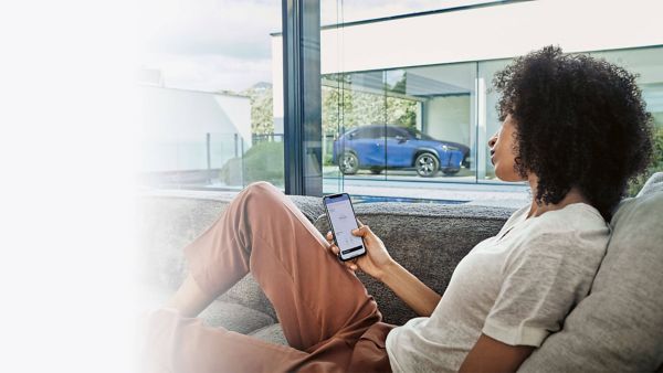 woman looking at her phone with a Lexus UX 300e in the background