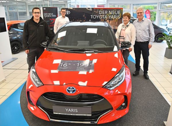 Roter Toyota Yaris im Autohaus umgeben von der Geschäftsleitung.