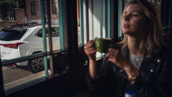 A Lexus UX driving past in the background  