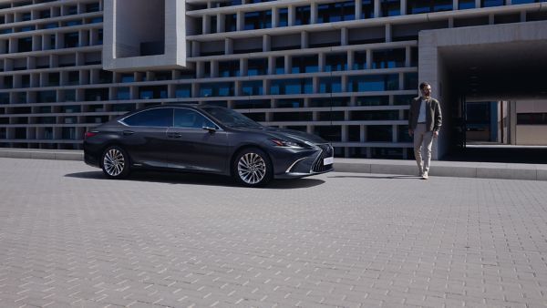 A man walking towards a parked Lexus ES