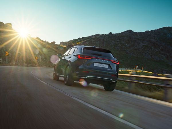 A rear view of the Lexus NX 450h+ driving 