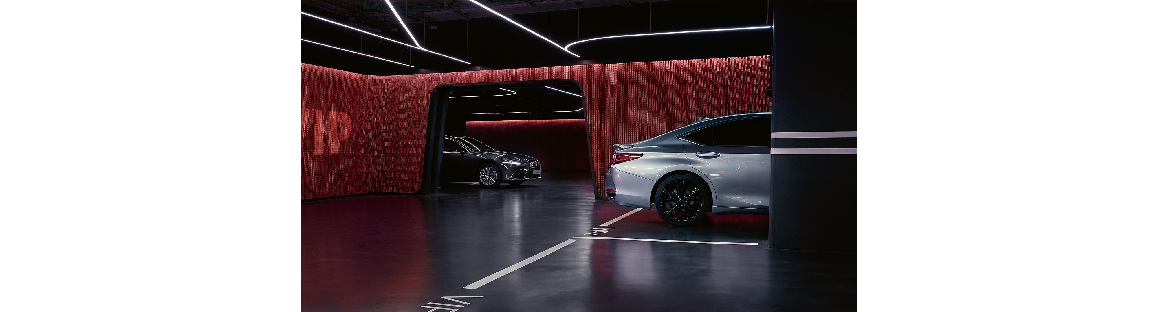 A silver and black Lexus ES parked in a lit up garage 