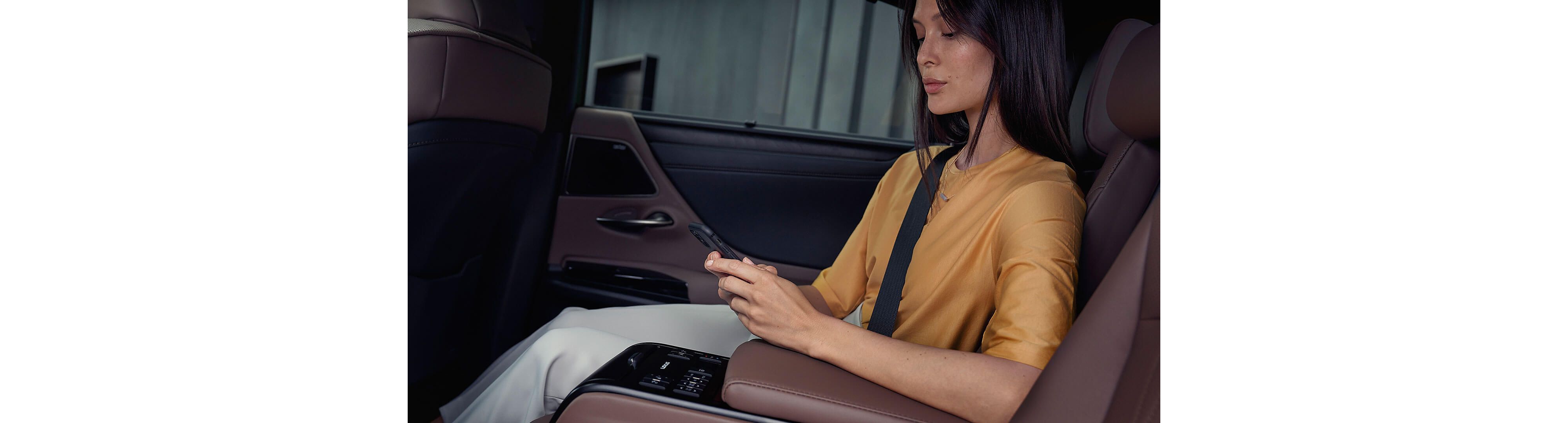 A woman on her phone sat in the rear passenger seat of a Lexus ES