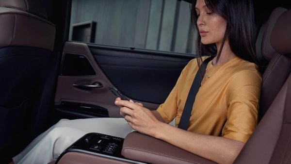 A woman on her phone sat in the rear passenger seat of a Lexus ES