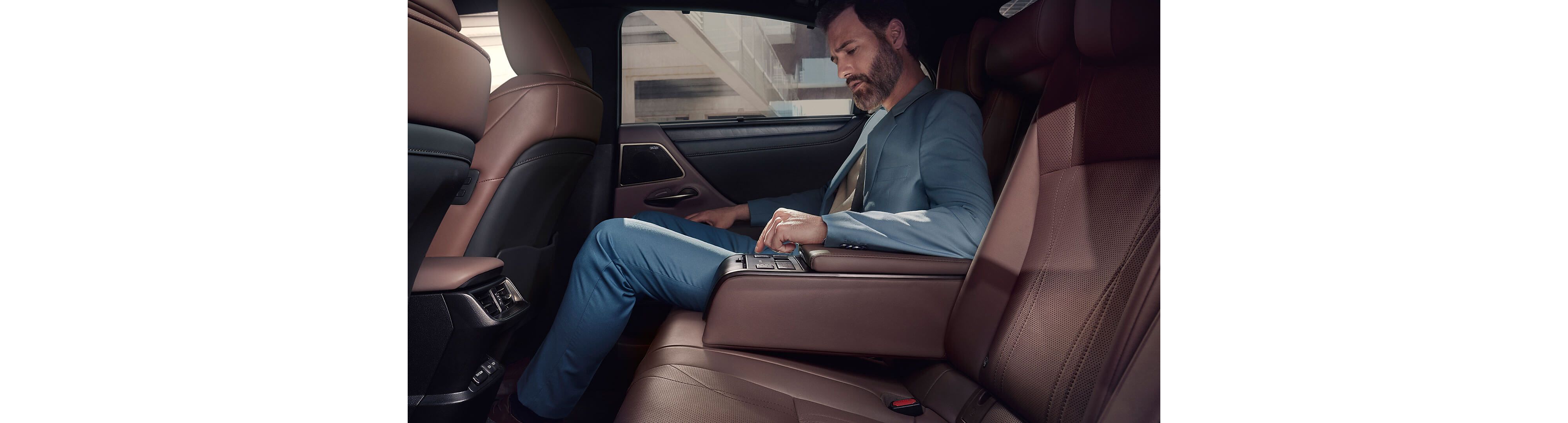 A man sat in the rear passenger seat of a Lexus ES