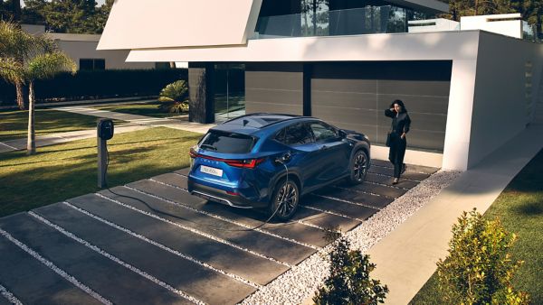 A Lexus NX plugged into a charging tower outside a home