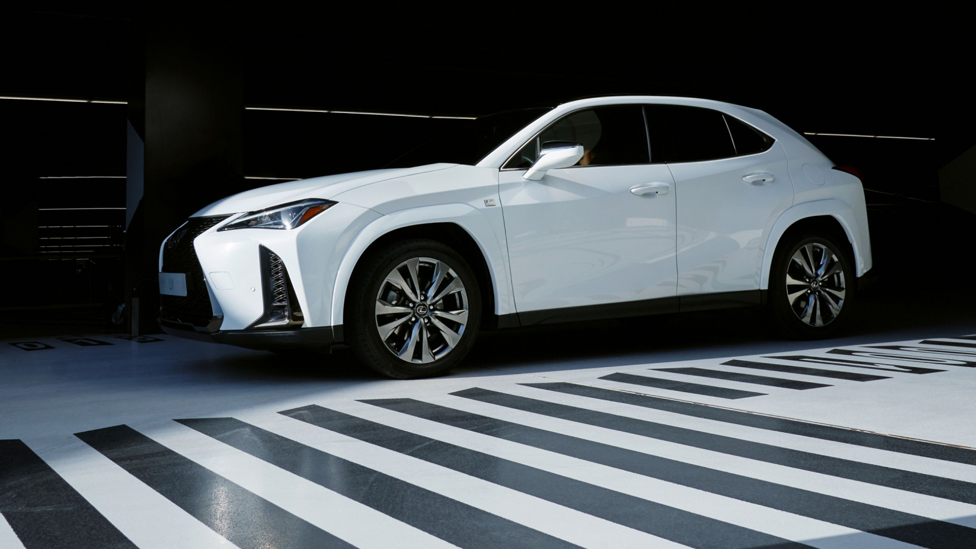 A white Lexus parked next to a black and white patterned floor